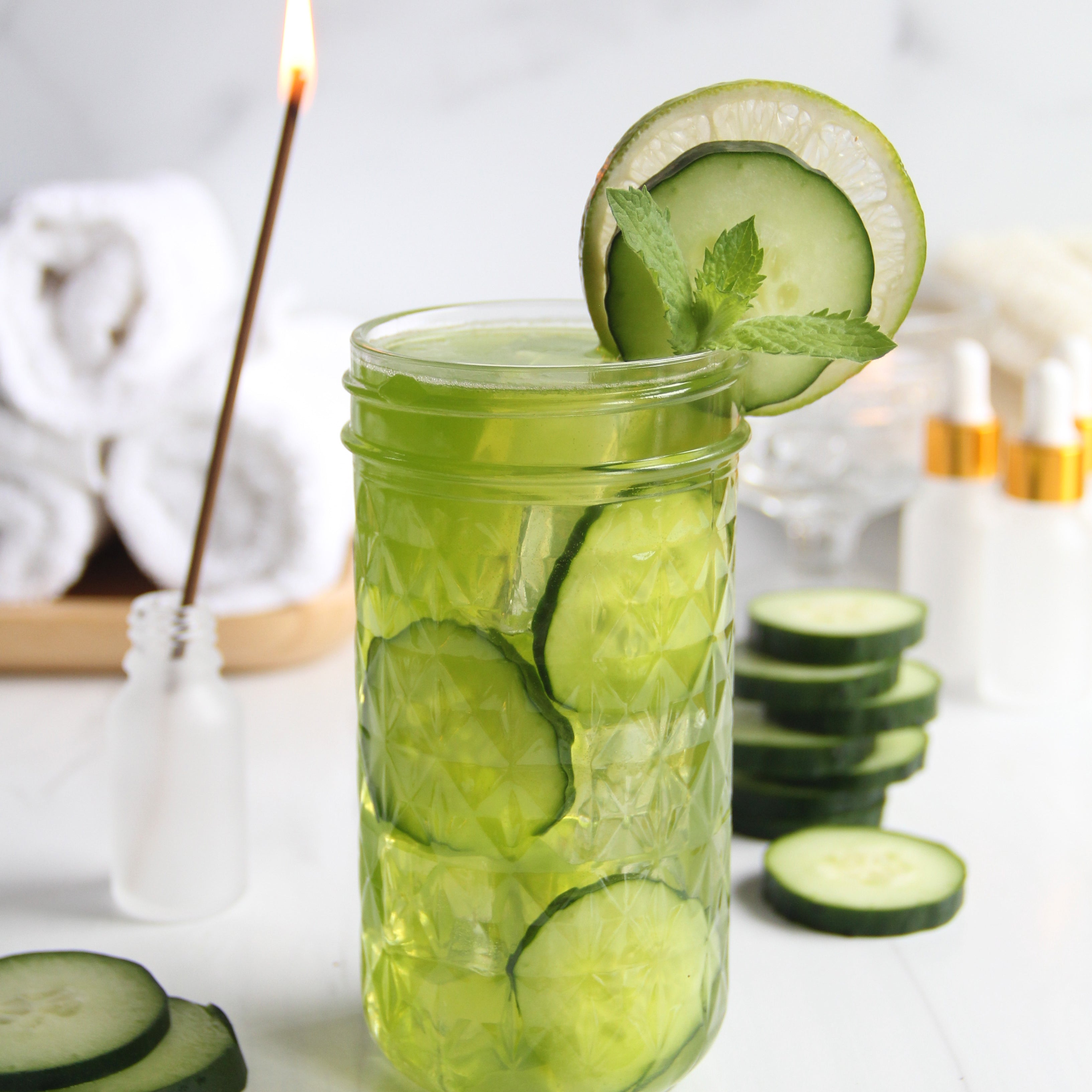 Refreshing Matcha Cucumber Lime Refresher served in a textured glass with cucumber slices, lime, and mint garnish, styled with spa-inspired elements in the background