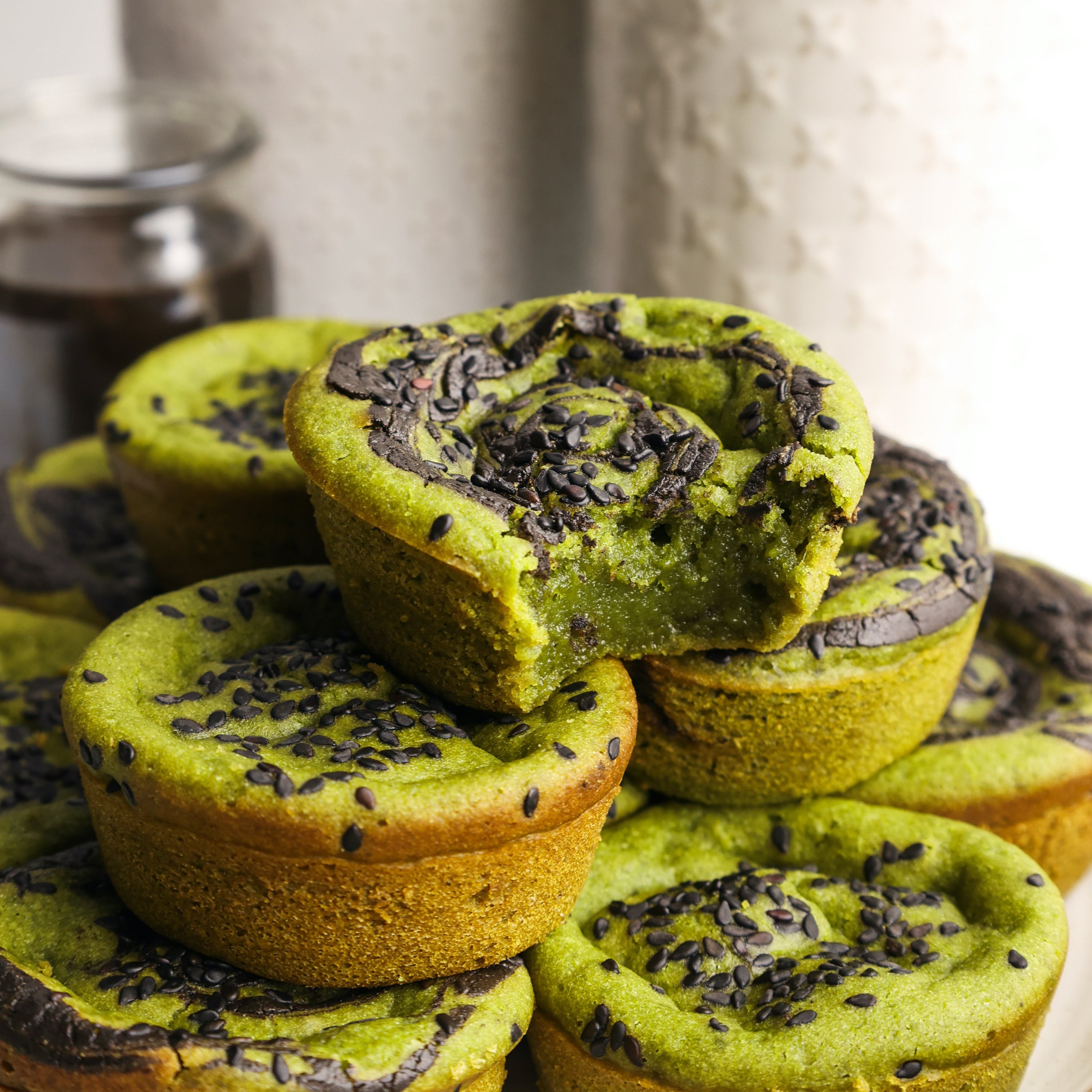 Black sesame matcha mochi muffins stacked on a plate.