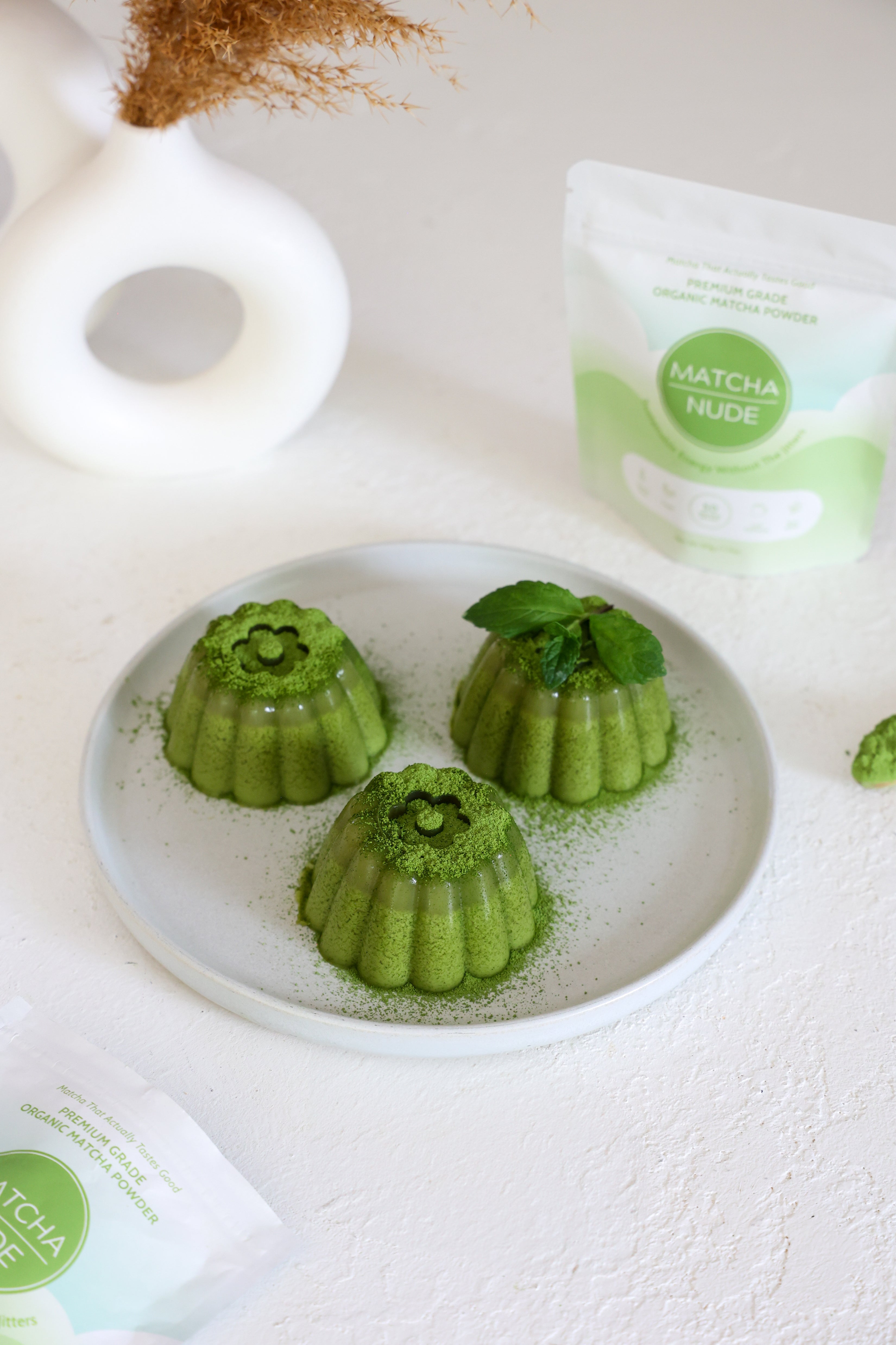 Green matcha panna cotta garnished with fresh mint on a ceramic plate.