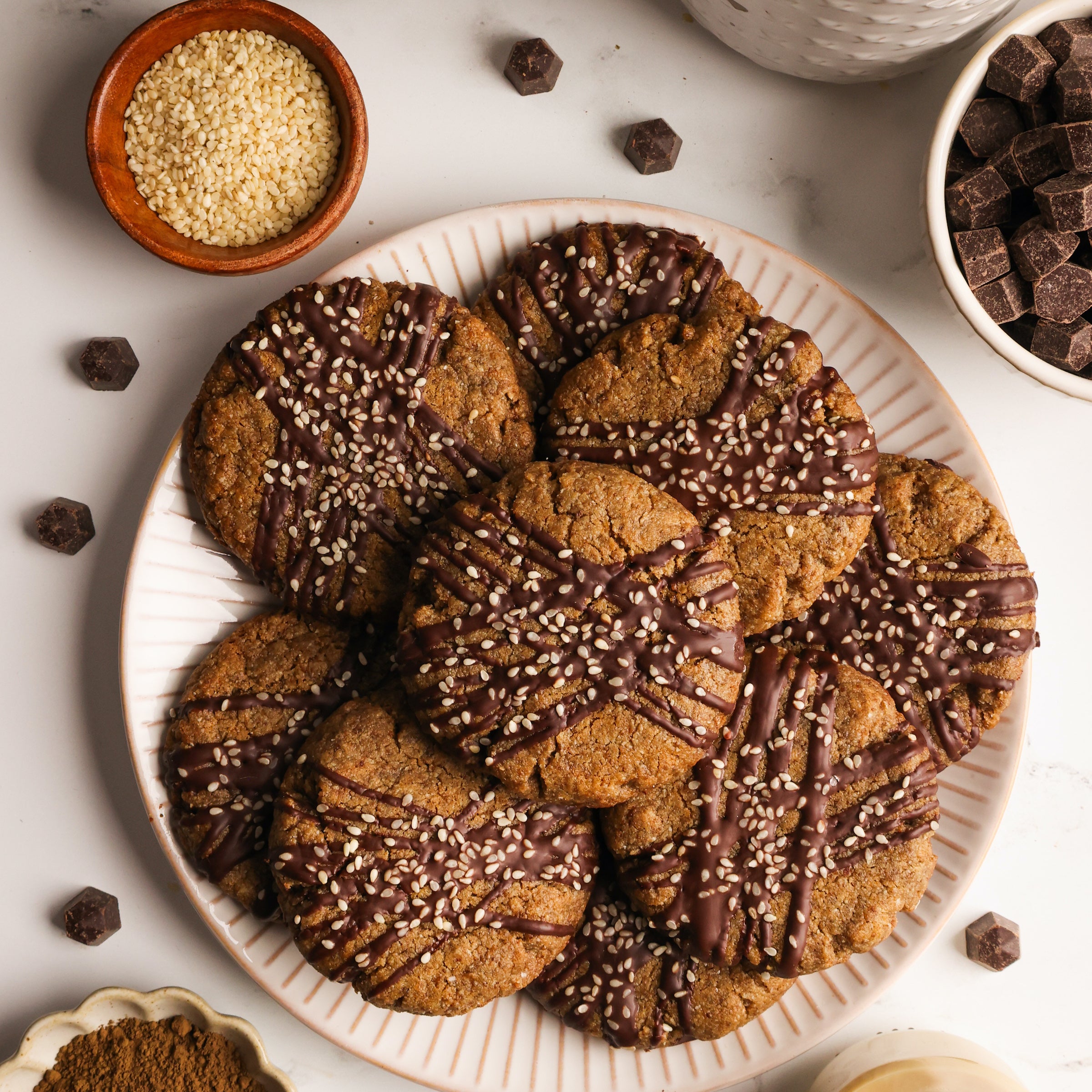 Hojicha tahini cookies drizzled with chocolate and topped with sesame seeds.