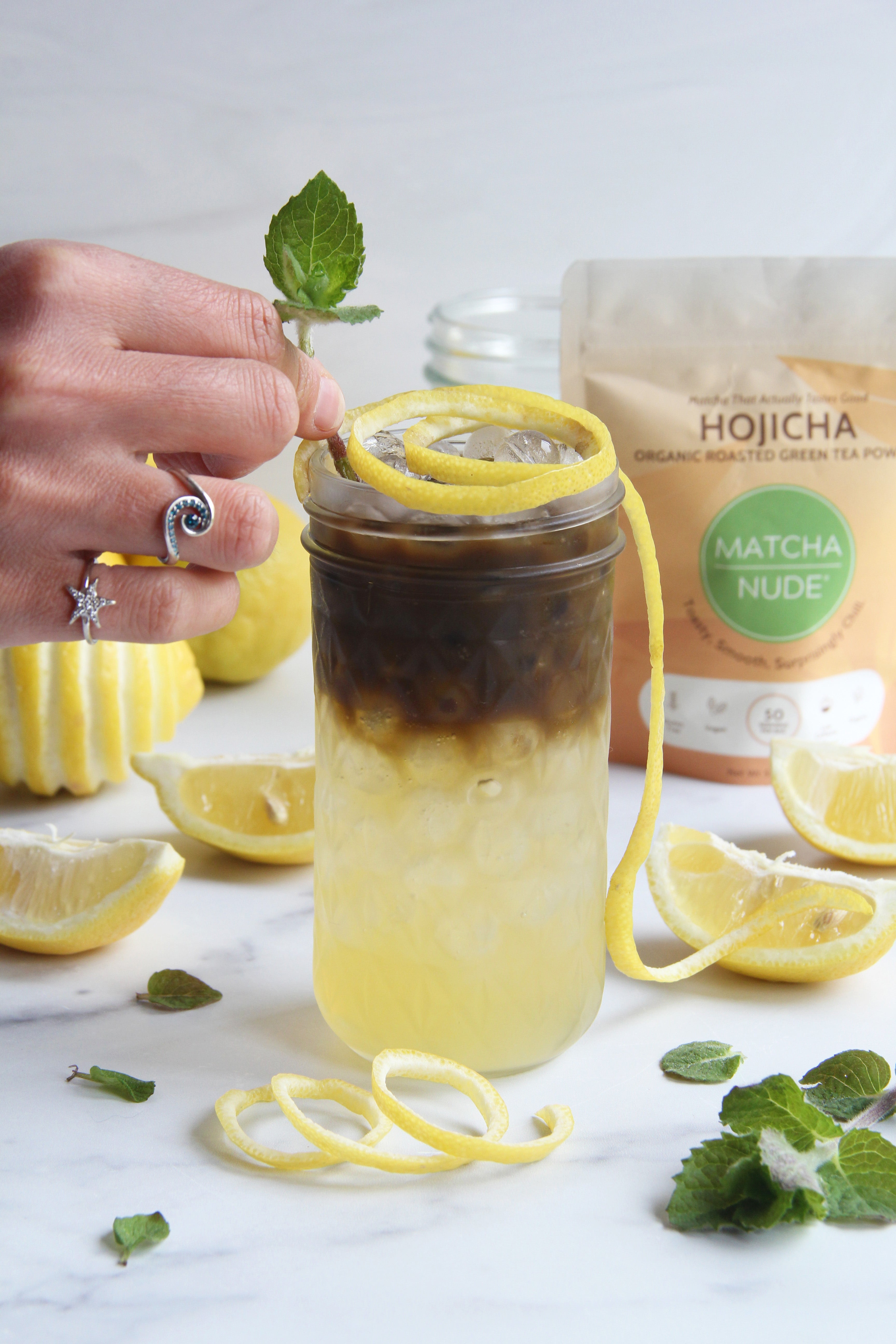 Hojicha Arnold Palmer made with Matcha Nude Hojicha Powder, fresh lemonade, ice, lemon peel, and mint garnish.