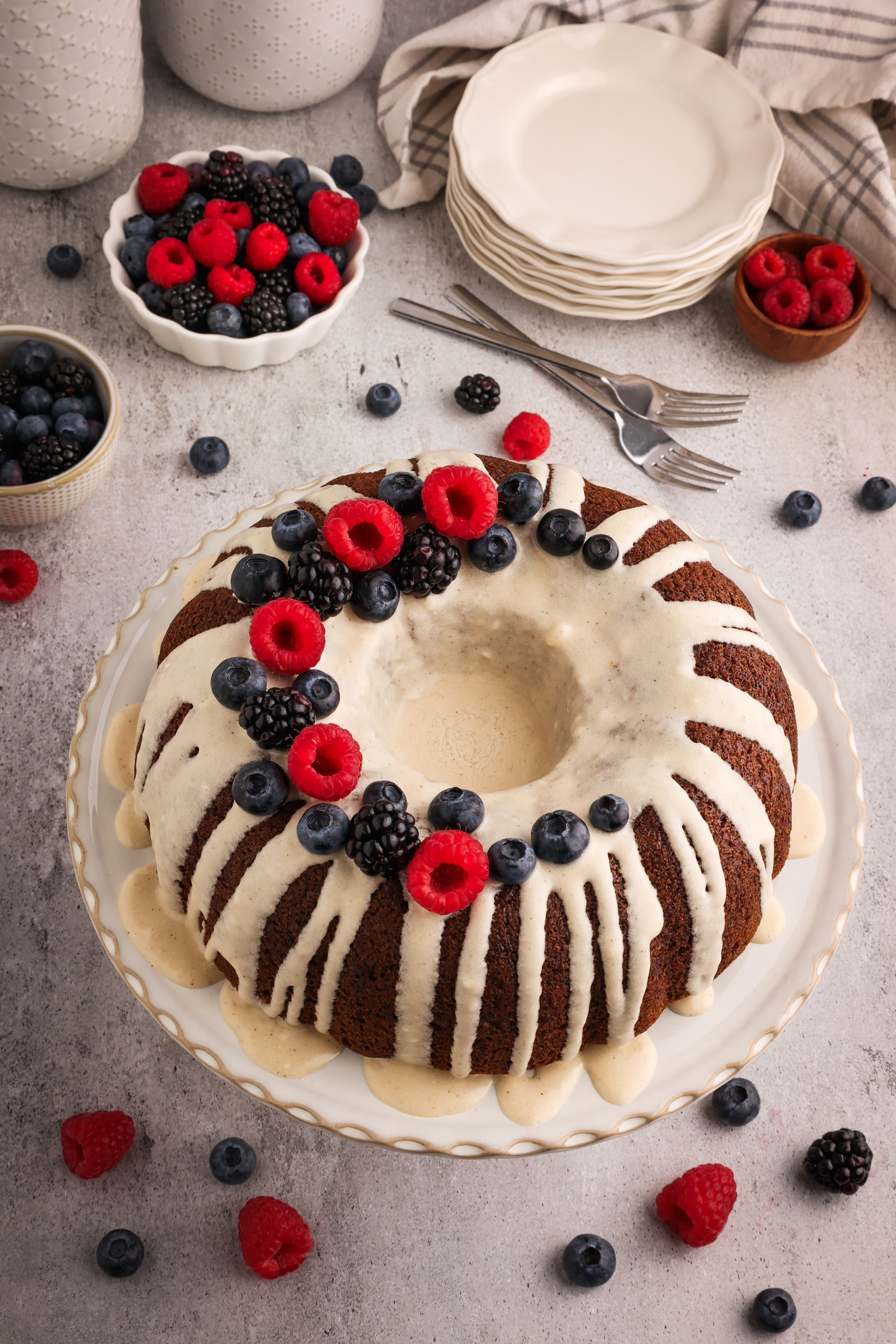 Moist hojicha vanilla bean Bundt cake drizzled with vanilla bean glaze and decorated with fresh raspberries, blueberries, and blackberries for an elegant dessert.