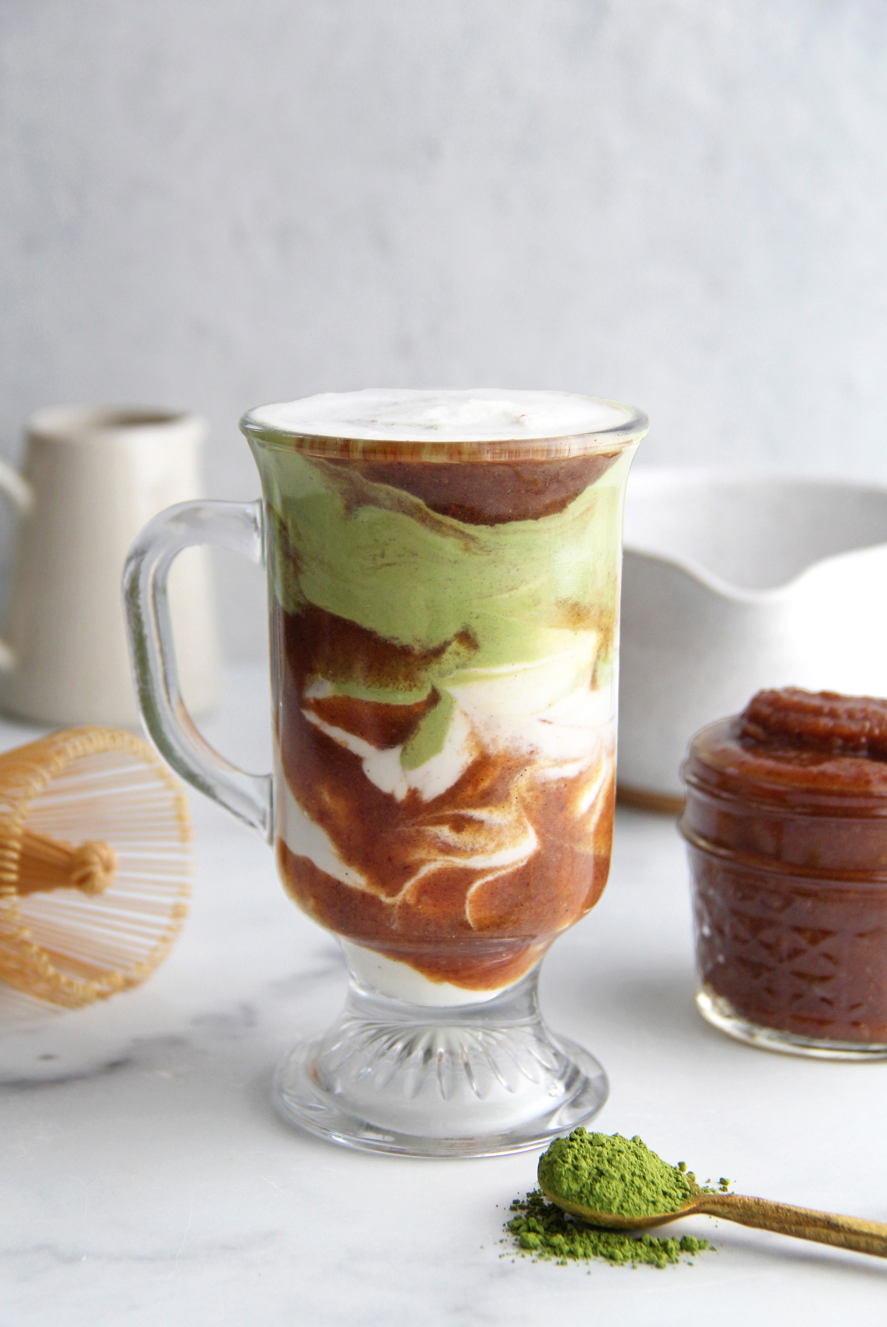 Vanilla Bean Date Caramel Matcha Latte layered with creamy milk, vibrant green matcha, and rich date caramel, topped with a layer of foam.