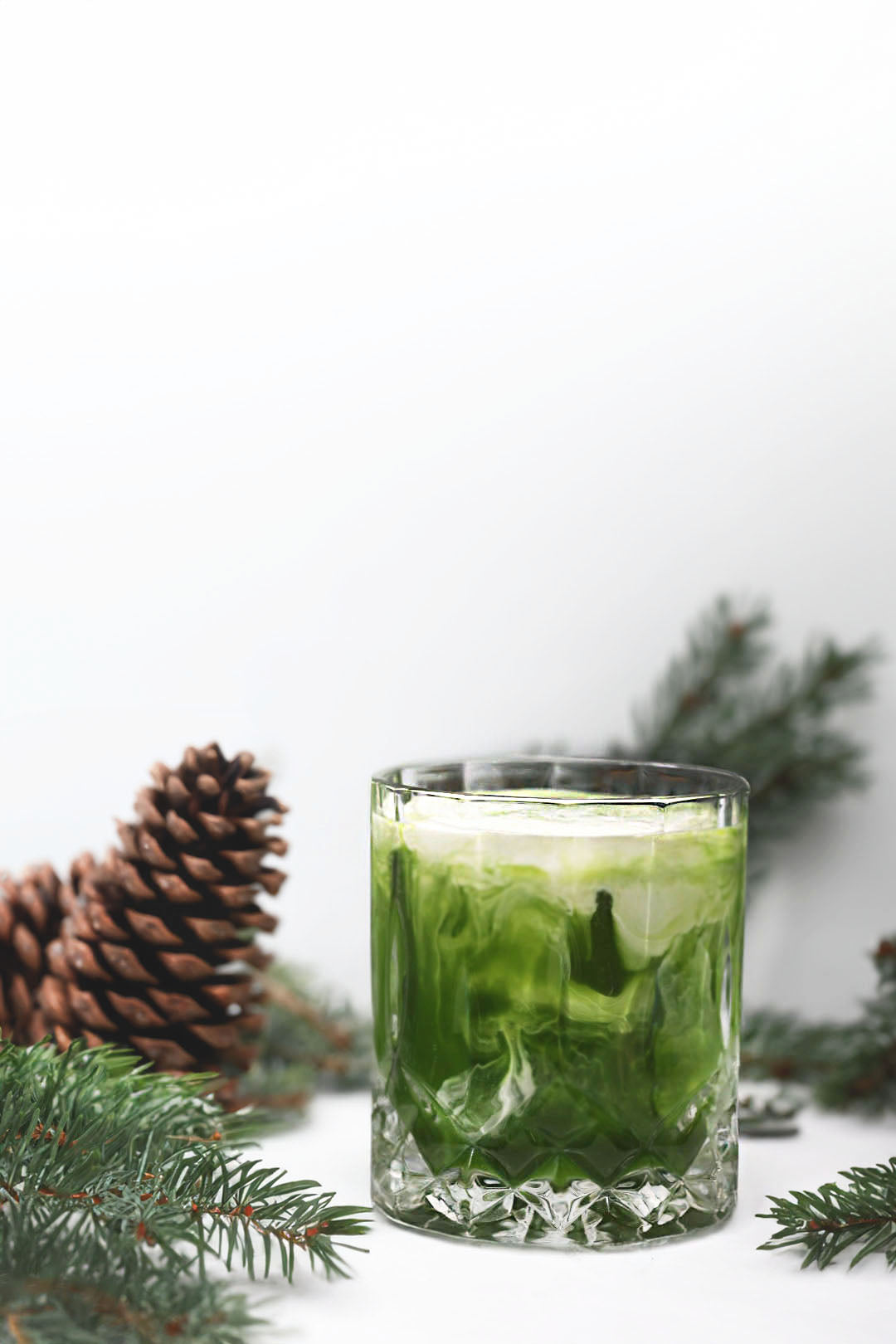 A crystal-clear glass filled with a beautifully layered Vanilla Matcha Russian cocktail, showcasing vibrant green matcha swirls blending elegantly with creamy white hues. 