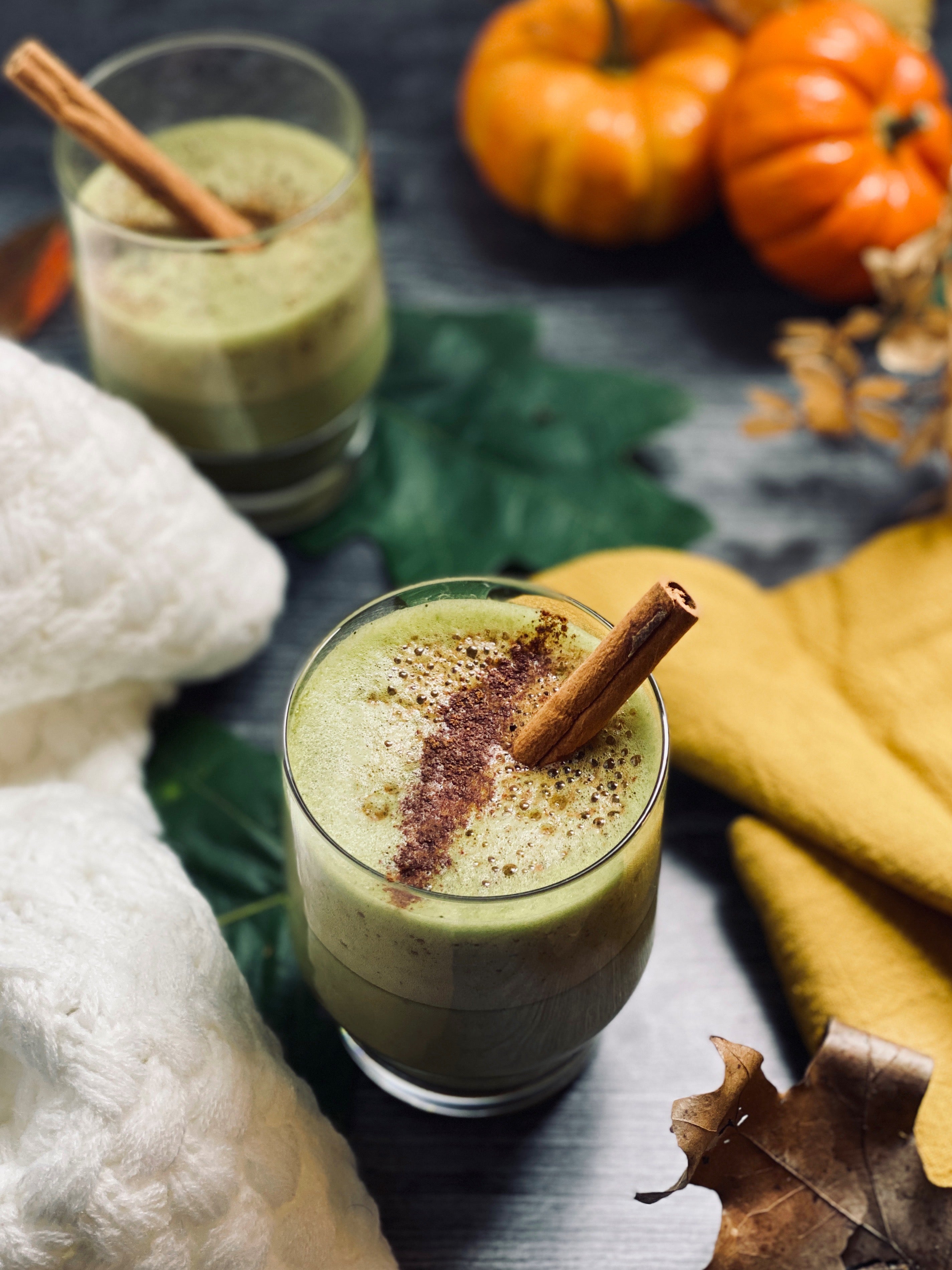  A pumpkin spice matcha latte in a glass, topped with a cinnamon stick and spice dusting, surrounded by pumpkins, a soft blanket, and autumn leaves for cozy fall vibes. 🍵🍂✨