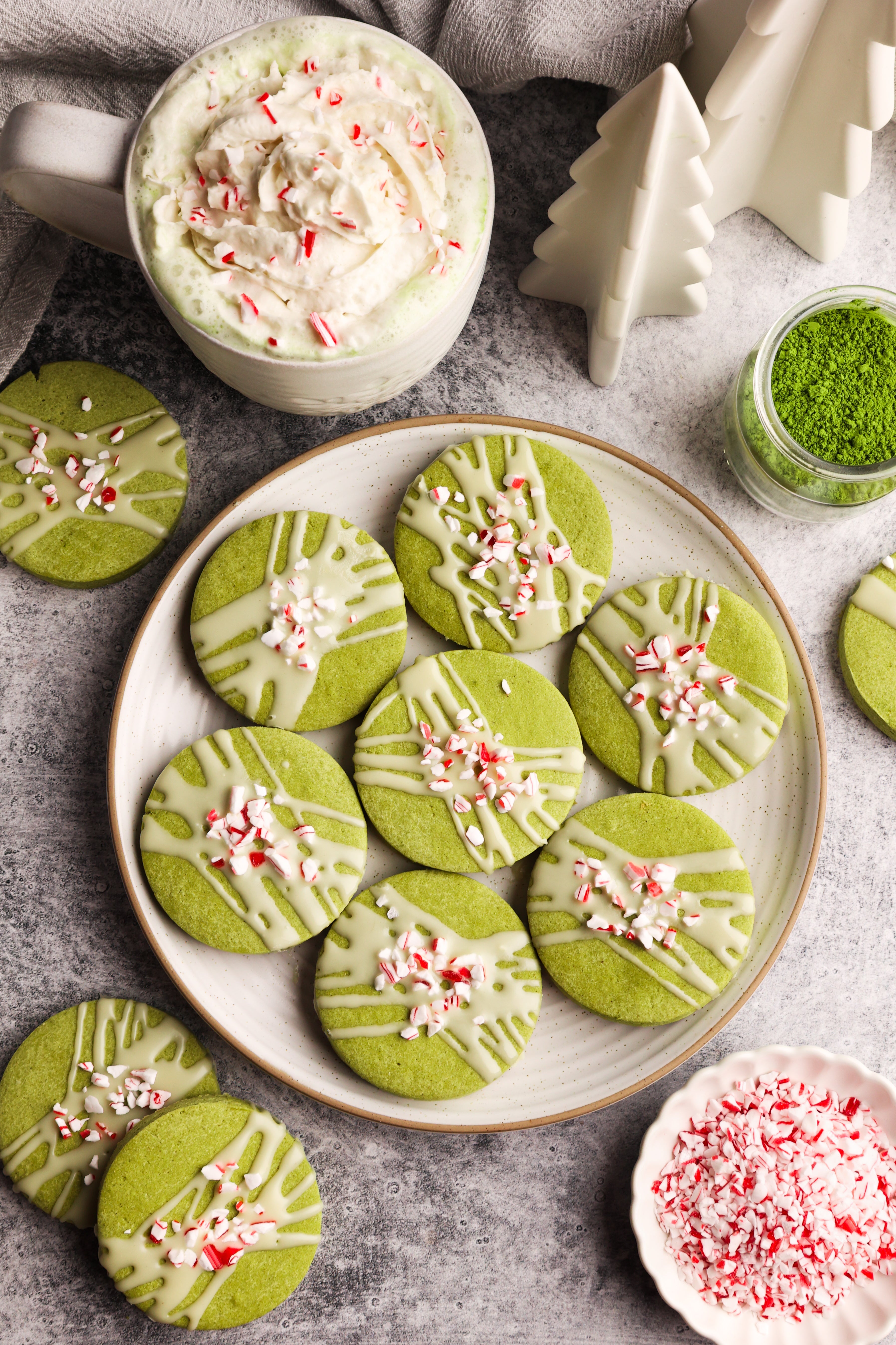 Matcha peppermint shortbread cookies with white chocolate drizzle and crushed candy canes, next to a festive matcha latte.
