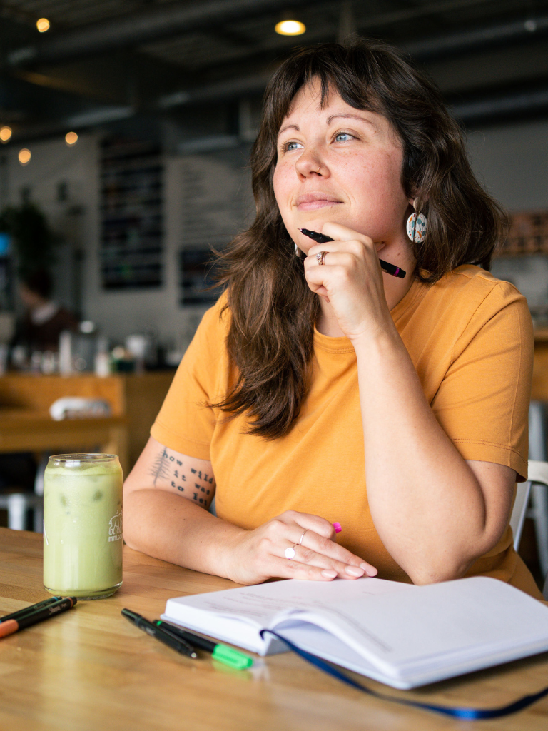 Owner of Matcha Nude, Samm look ahead with an iced matcha latte on the table and a pen in her hand