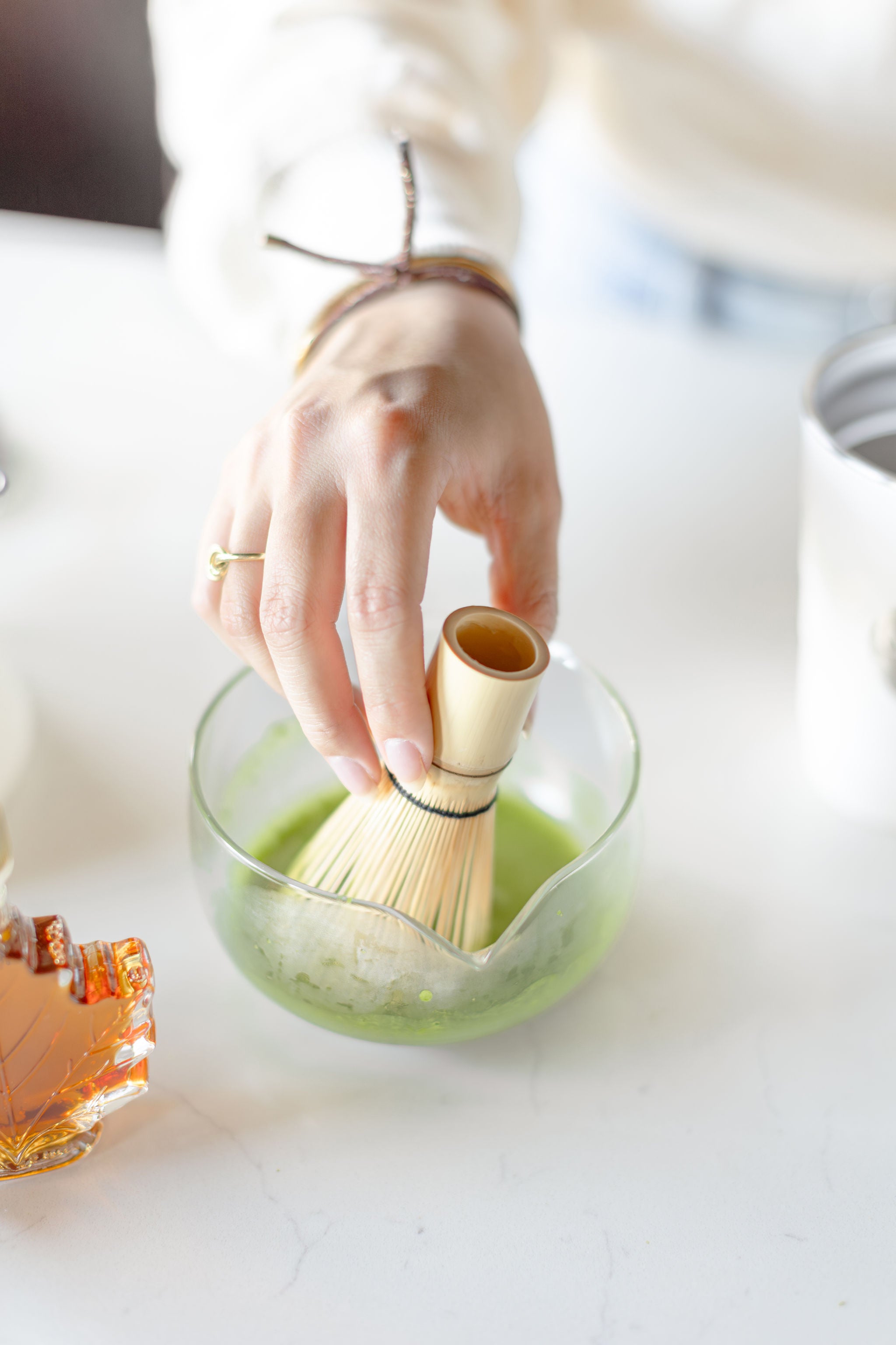 Hand holding a vibrant green matcha latte topped with dried rose petals made with premium organic Japanese matcha