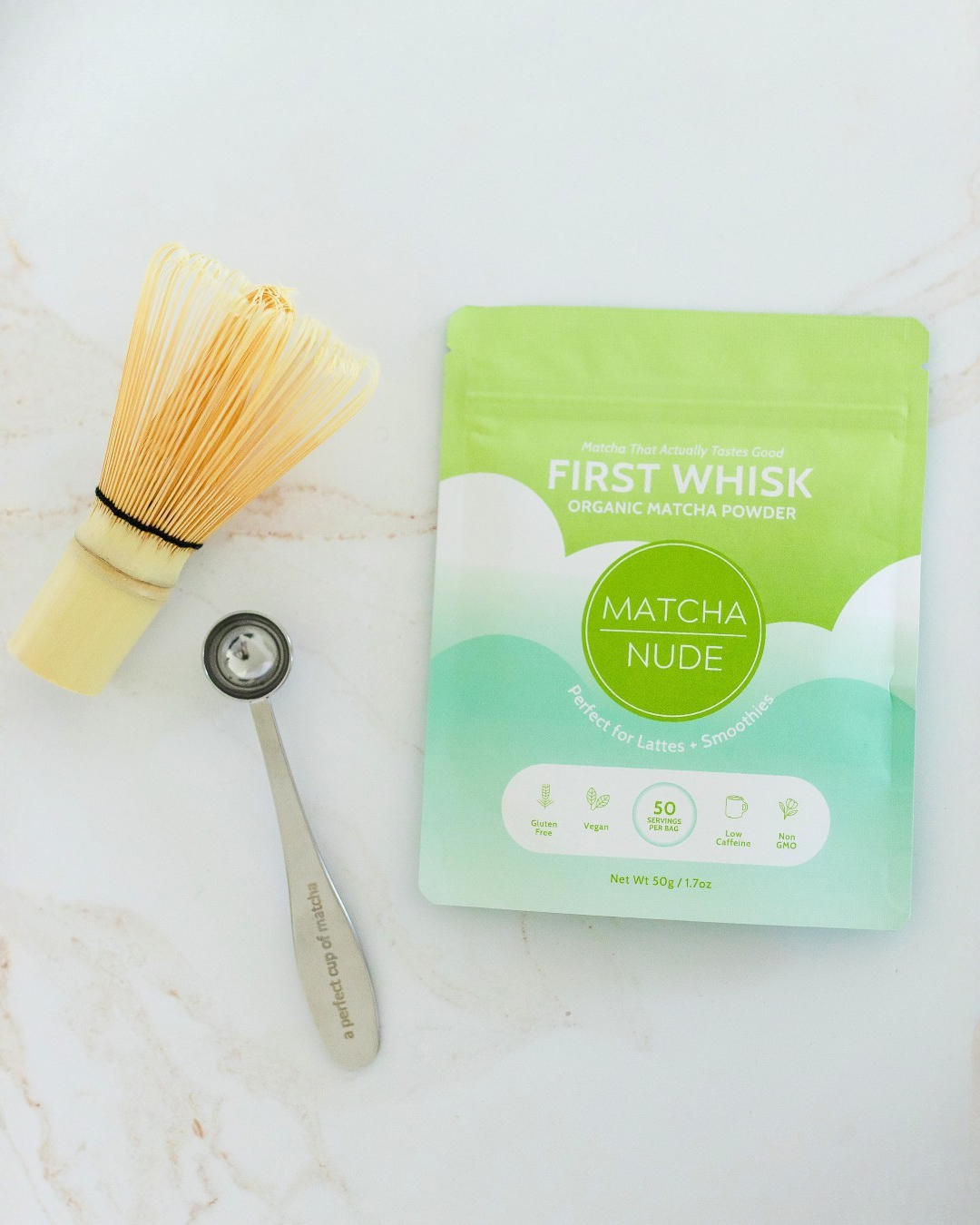 Beginner matcha starter kit with First Whisk matcha, bamboo whisk, and matcha spoon on marble surface