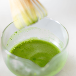 Close-up of vibrant green Premium Matcha being whisked in glass bowl