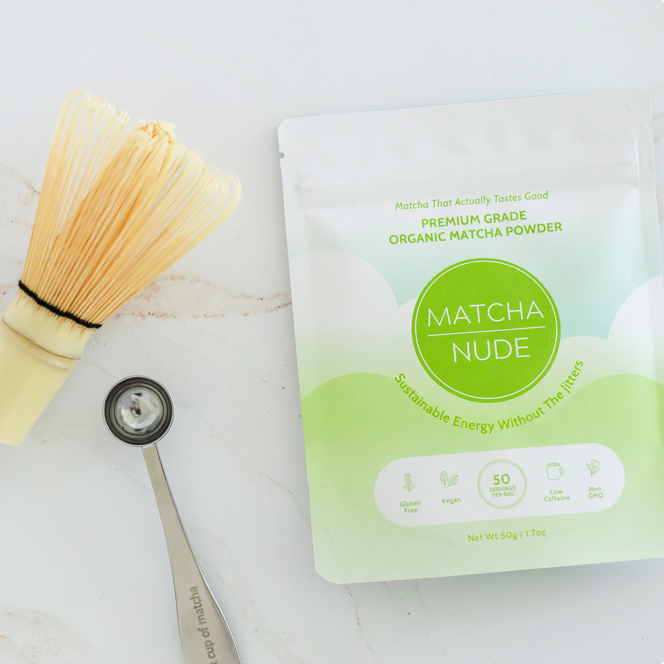 Flat lay of Matcha Nude Premium Matcha with bamboo whisk and matcha spoon