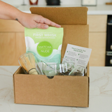 Hand holding First Whisk organic matcha above open matcha ritual set box