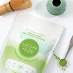 Premium organic matcha powder by Matcha Nude showcased with a traditional bamboo whisk and a green ceramic whisk holder. This sustainable matcha brand offers clean energy without jitters, featuring gluten-free, vegan, and non-GMO benefits. Perfect for matcha enthusiasts seeking quality and eco-friendly choices.