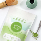 Premium organic matcha powder by Matcha Nude showcased with a traditional bamboo whisk and a green ceramic whisk holder. This sustainable matcha brand offers clean energy without jitters, featuring gluten-free, vegan, and non-GMO benefits. Perfect for matcha enthusiasts seeking quality and eco-friendly choices.