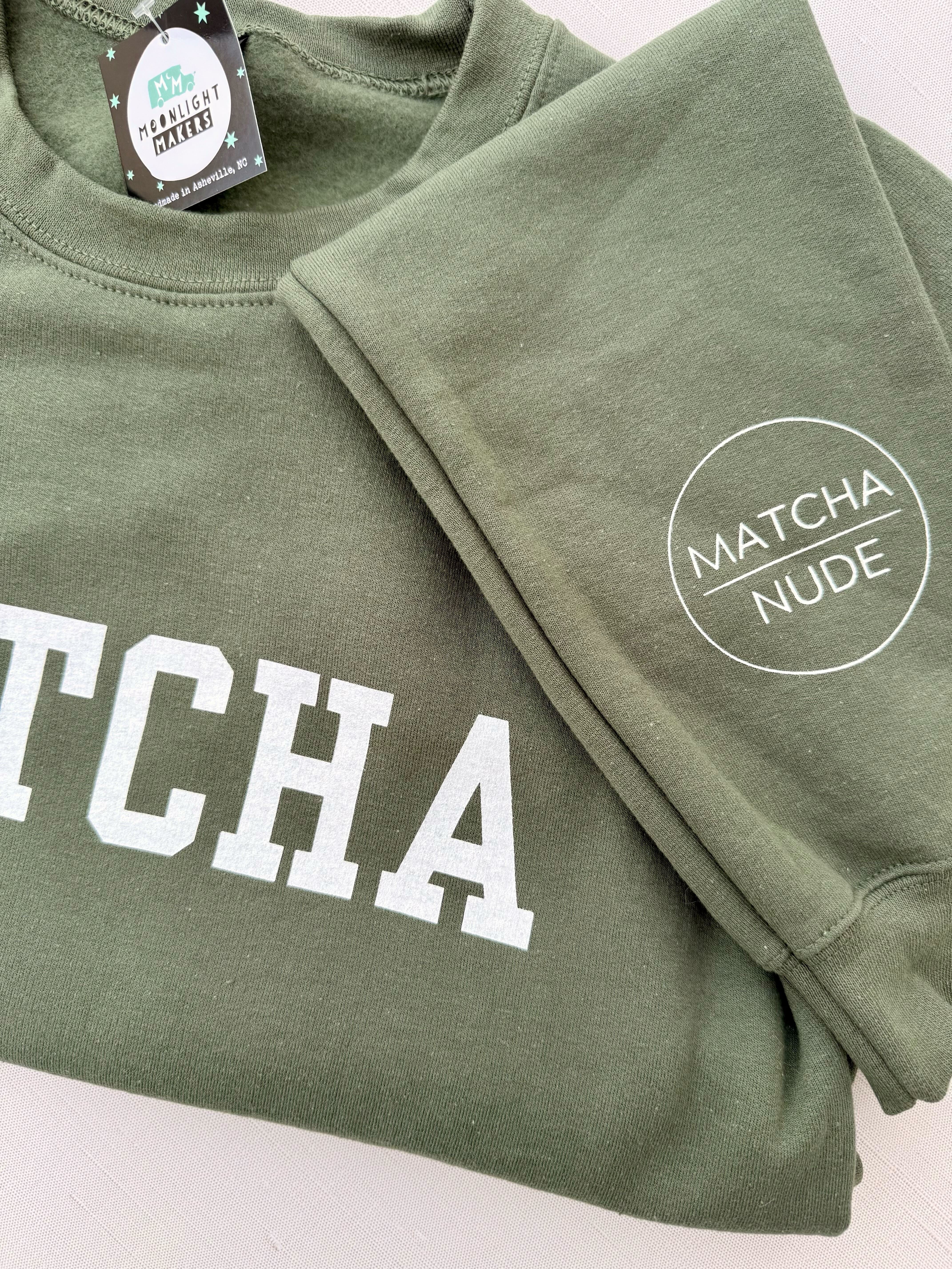 Unisex green MATCHA crewneck sweatshirt with Matcha Nude sleeve logo – printed by Moonlight Makers in Asheville, NC