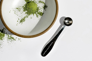 A perfect cup of matcha spoon next to a bowl with matcha powder